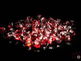 a pile of red and white glass beads on a black surface