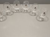 six verres à vin vides posés sur une table, avec un anneau doré sur le bord