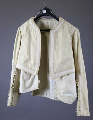 une veste blanche suspendue à un cintre contre un mur gris