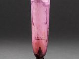 un vase en verre rose posé sur un socle en bois