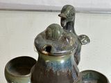 une photo représentant une théière et quatre tasses posées sur une table