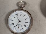 a silver pocket watch with roman numerals on it