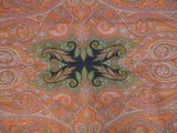 an orange and green paisley print fabric with a cross in the center