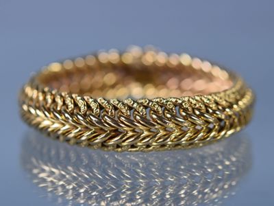 gros plan d'une bague en or sur une surface réfléchissante