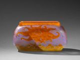 un vase orange et violet posé sur une table blanche