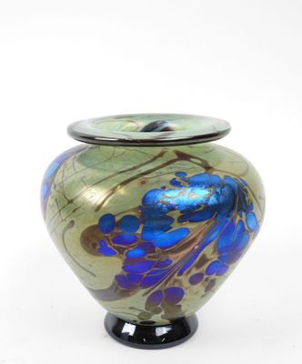 un vase bleu et vert posé sur une surface blanche