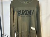 un sweat-shirt vert accroché à un portant dans un magasin de vêtements