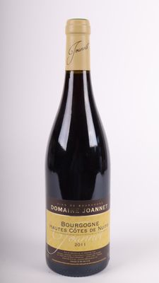the bottle of wine is sitting on the table on a white surface