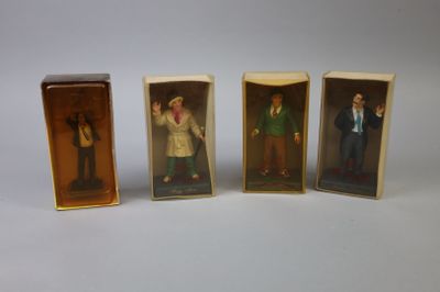 three miniature figurines of people in boxes on a white surface