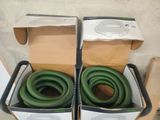 deux boîtes posées par terre, contenant des tuyaux verts