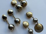 some gold and silver bells are laying on a white surface