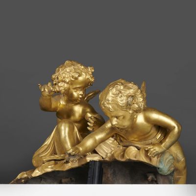 paire de figurines dorées représentant des chérubins, posées sur un socle en marbre
