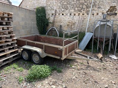 a trailer that is parked next to a pile of pallets