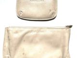 pair of white leather purses with zippers sitting on a white surface