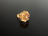 a close up of a gold ring with pink stones on a black surface