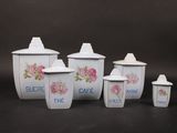 five white canisters with pink roses on them on a black background