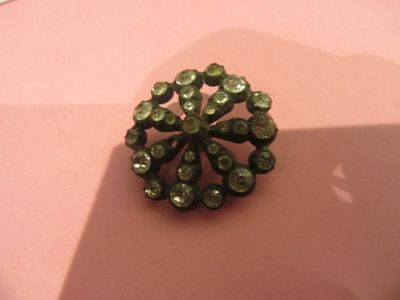 a green brooch on top of a pink surface