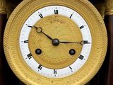 a gold clock with roman numerals on the face