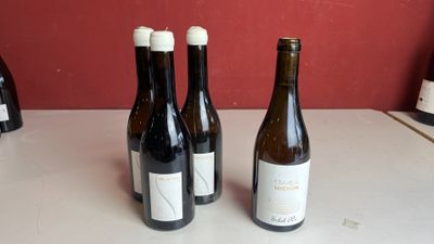 trois bouteilles de vin sont alignées sur un plan de travail