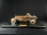 une maquette ancienne en bronze représentant une voiture avec un homme au volant