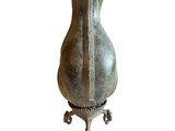 a metal vase that is sitting on a stand
