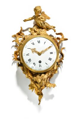 a gold clock on a white wall with a statue on top of it