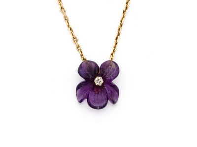 un collier orné d'une fleur violette avec un diamant au centre, monté sur une chaîne en or