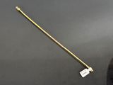 a gold plated stick with a long handle on a black surface