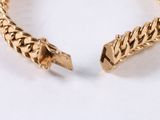 a close up of a gold bracelet on a white surface