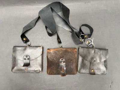 trois sacs à main en cuir accrochés à un mur métallique