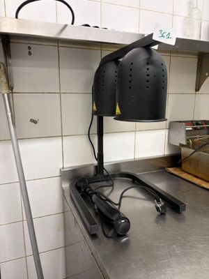 une lampe noire posée sur un plan de travail en métal dans une cuisine