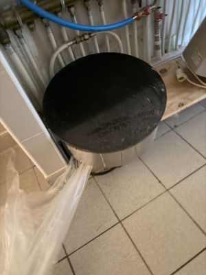 a black stool in the middle of a tiled floor