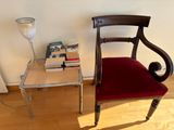 a red chair sitting next to a table with a lamp on top of it