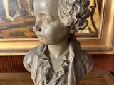 statue of a boy in a suit on a table in front of a painting