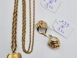 a close up of a gold necklace with a heart pendant and other items