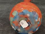 a small orange and blue vase with a tag on it