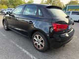 the rear end of a black car parked in a parking lot
