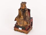 une statue en or représentant un homme assis sur une chaise