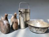 three vases, a bowl, and a bottle sitting on a table