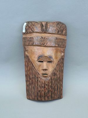 gros plan d'un masque en bois sur une surface grise