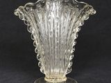 un vase en verre posé sur un socle, sur fond noir