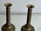 pair of antique brass candlesticks on glass table with white background