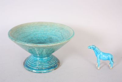a small toy horse standing next to a blue bowl