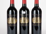 trois bouteilles de vin rouge posées l'une à côté de l'autre sur une surface blanche