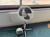 un ventilateur posé par terre près d'une fenêtre