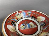 a red plate with a design on it next to a cup and saucer