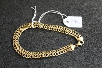 gros plan d'un bracelet en chaîne en or sur une surface noire