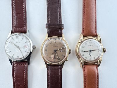 trois types de montres sont alignés sur une surface blanche