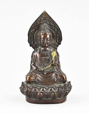 une statue en bronze représentant un Bouddha assis sur une fleur de lotus