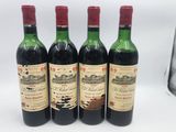 quatre bouteilles de vin sont alignées sur une surface blanche